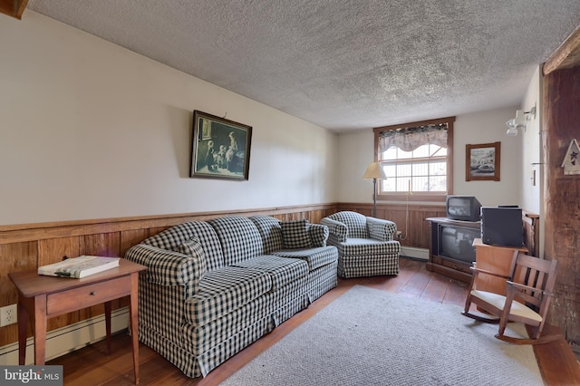 living area featuring a textured ceiling, hardwood / wood-style floors, wainscoting, and a baseboard radiator