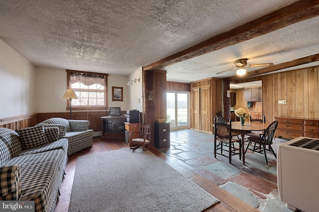 living area with stone tile flooring, wood walls, a textured ceiling, and a wainscoted wall