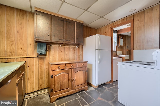 kitchen with white appliances, washer / clothes dryer, a drop ceiling, and wooden walls