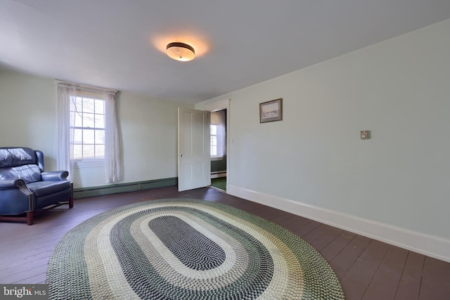 living area featuring a baseboard heating unit, baseboards, and hardwood / wood-style floors