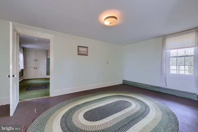 spare room with a baseboard heating unit, wood-type flooring, and baseboards