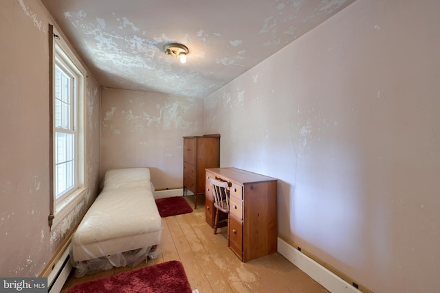 bedroom with light wood-type flooring, a baseboard radiator, and baseboards