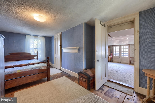 bedroom with a textured ceiling, hardwood / wood-style floors, and baseboards