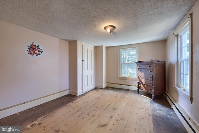 interior space featuring baseboards, hardwood / wood-style flooring, baseboard heating, a textured ceiling, and a baseboard heating unit