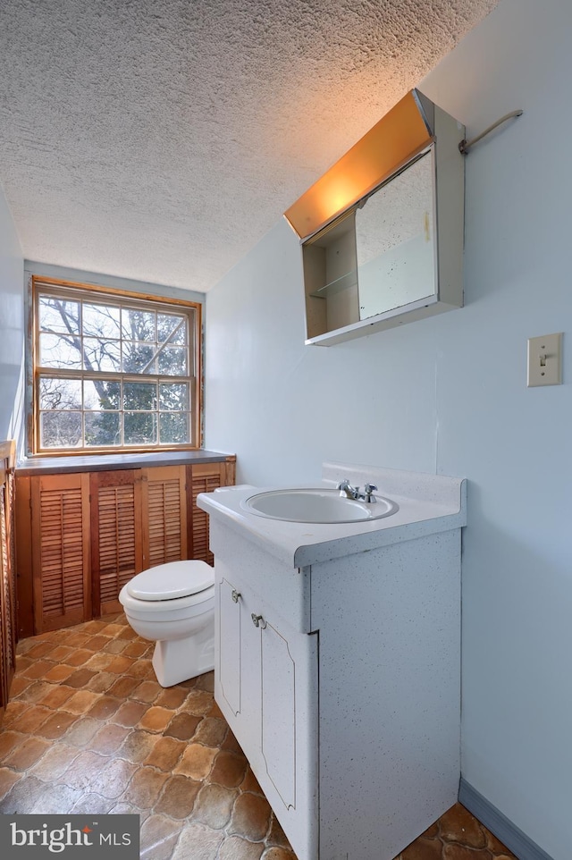 bathroom with toilet, a textured ceiling, and vanity