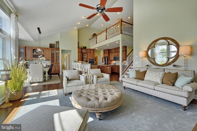 living area with a ceiling fan, wood finished floors, stairs, high vaulted ceiling, and recessed lighting