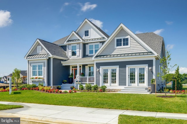 craftsman-style house with board and batten siding, a front yard, a standing seam roof, and roof with shingles