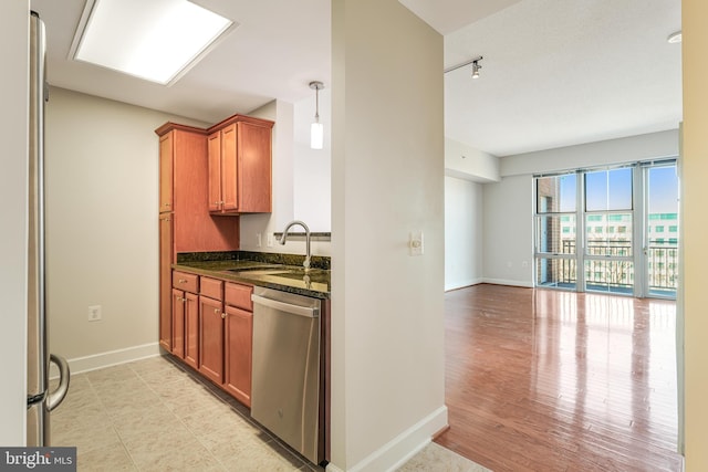 kitchen with dark stone countertops, baseboards, appliances with stainless steel finishes, and a sink