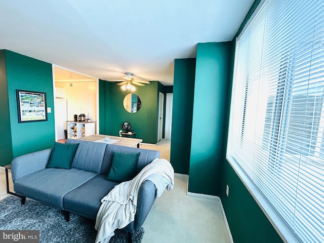 carpeted living area featuring ceiling fan and baseboards