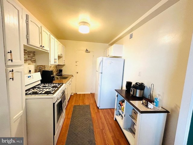 kitchen with white appliances, visible vents, light wood-style floors, white cabinetry, and backsplash