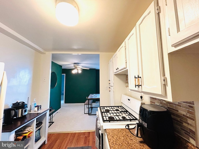 kitchen with light countertops, dark wood-type flooring, a ceiling fan, white cabinetry, and white gas range oven