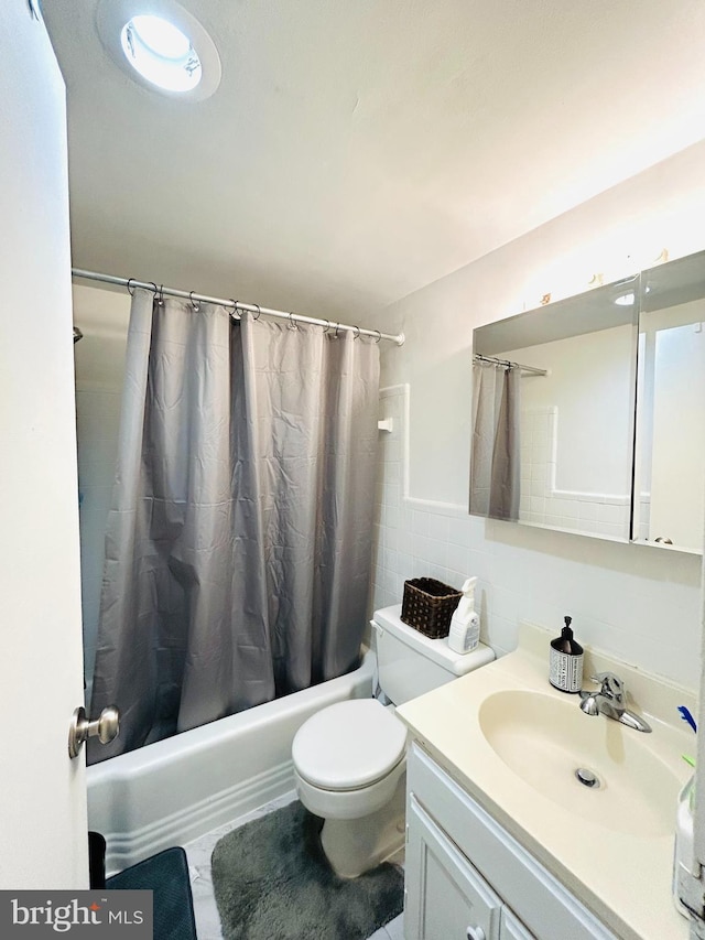 bathroom with tile walls, vanity, toilet, and shower / bath combo with shower curtain