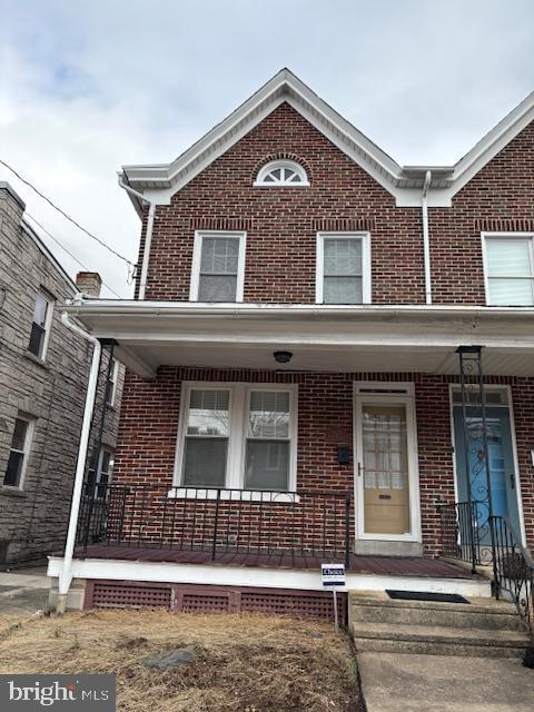 multi unit property featuring a porch and brick siding