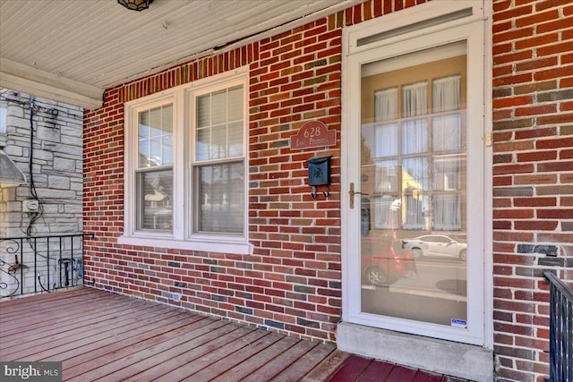 view of exterior entry featuring brick siding and covered porch