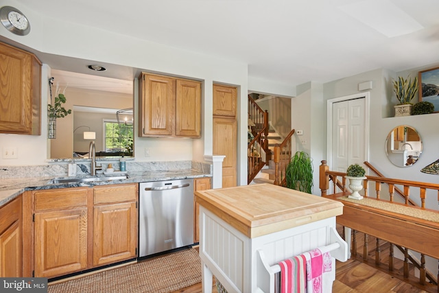 kitchen with a sink, light wood-style floors, wooden counters, and dishwasher