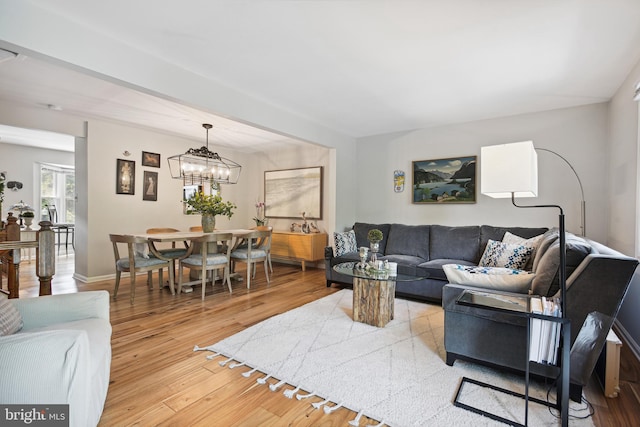 living room with baseboards, an inviting chandelier, and wood finished floors