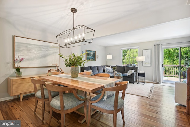 dining space with an inviting chandelier, wood-type flooring, and baseboards