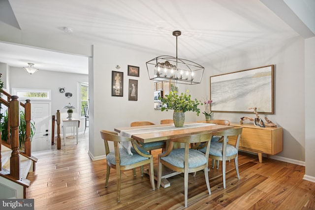 dining space featuring light wood-style floors, stairs, and baseboards