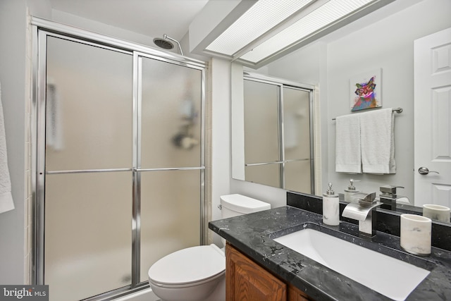 full bathroom with vanity, a shower stall, and toilet