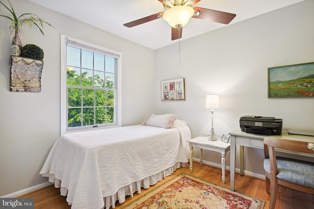 bedroom with a ceiling fan, light wood-style flooring, and baseboards