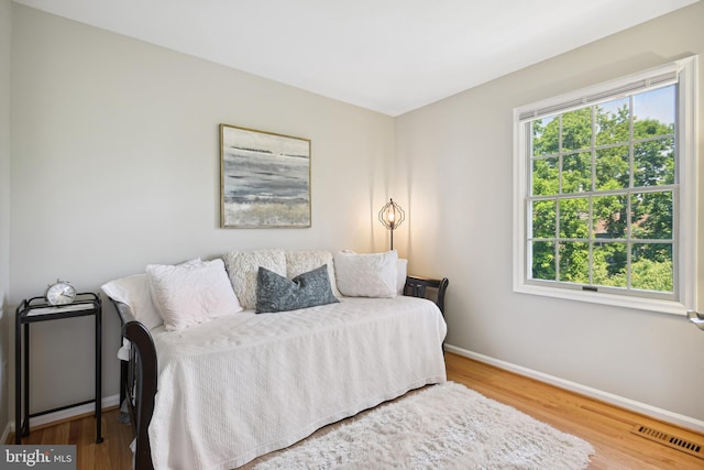 bedroom with wood finished floors, visible vents, baseboards, and multiple windows