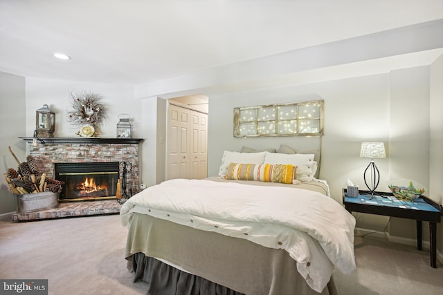 bedroom with a closet, a brick fireplace, carpet flooring, and baseboards