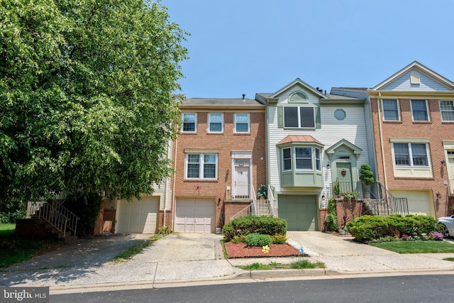 multi unit property with a garage, concrete driveway, brick siding, and stairs