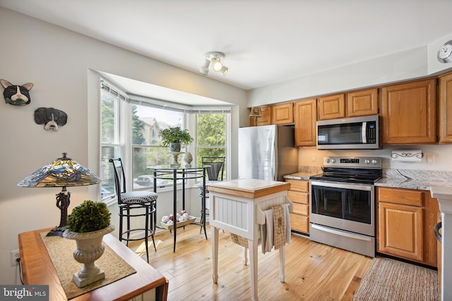 kitchen featuring light wood-style flooring, appliances with stainless steel finishes, and brown cabinets