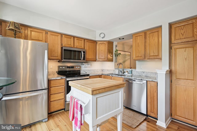 kitchen with stainless steel appliances, butcher block countertops, a sink, and light wood-style flooring