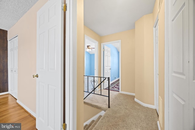 hallway with carpet, an upstairs landing, and baseboards