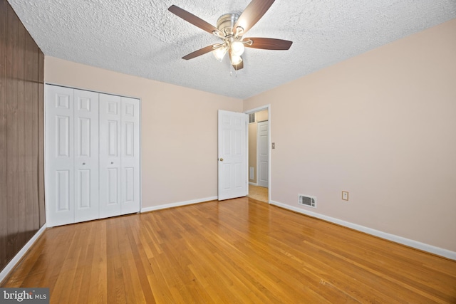 unfurnished bedroom featuring baseboards, visible vents, a textured ceiling, light wood-type flooring, and a closet