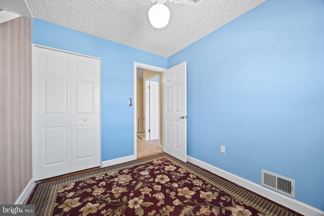 unfurnished bedroom featuring baseboards, visible vents, and a textured ceiling