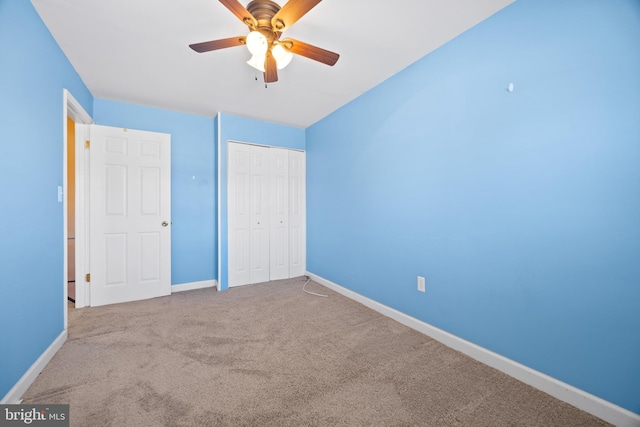 unfurnished bedroom featuring carpet floors, a closet, baseboards, and a ceiling fan