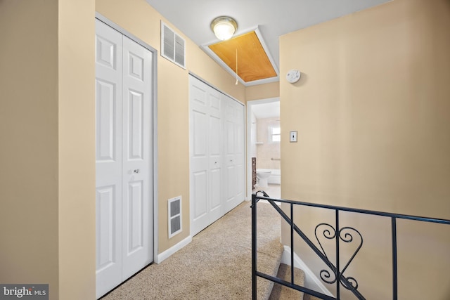 hall featuring attic access, visible vents, and an upstairs landing