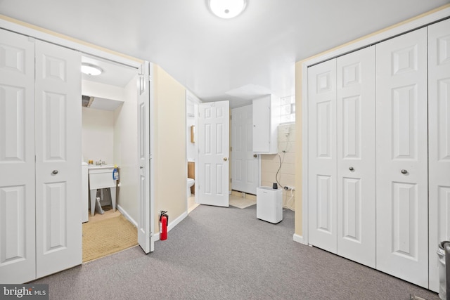 carpeted bedroom with ensuite bathroom, a closet, and baseboards