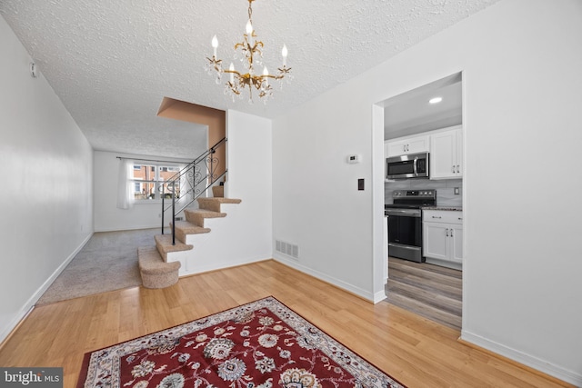 foyer entrance featuring stairway, light wood-style flooring, visible vents, and baseboards