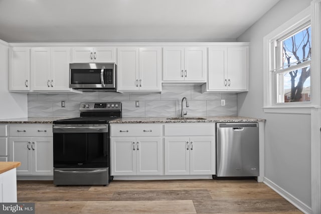 kitchen with backsplash, appliances with stainless steel finishes, white cabinets, and a sink