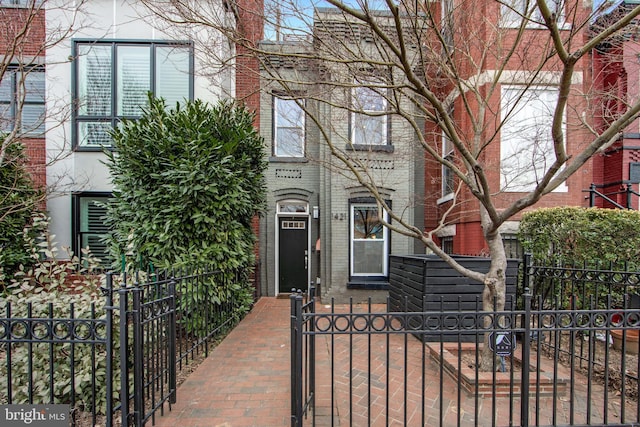 view of front facade with brick siding, a gate, and a fenced front yard
