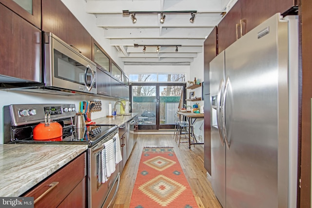 kitchen featuring glass insert cabinets, track lighting, light wood-type flooring, appliances with stainless steel finishes, and beam ceiling