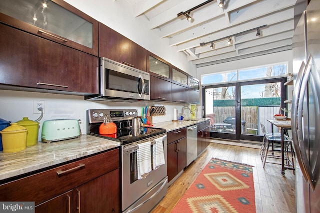 kitchen with light wood finished floors, a sink, rail lighting, and stainless steel appliances