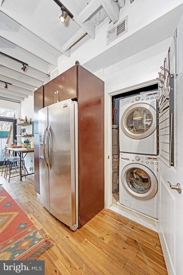 laundry area with visible vents, light wood-type flooring, laundry area, stacked washer and dryer, and rail lighting
