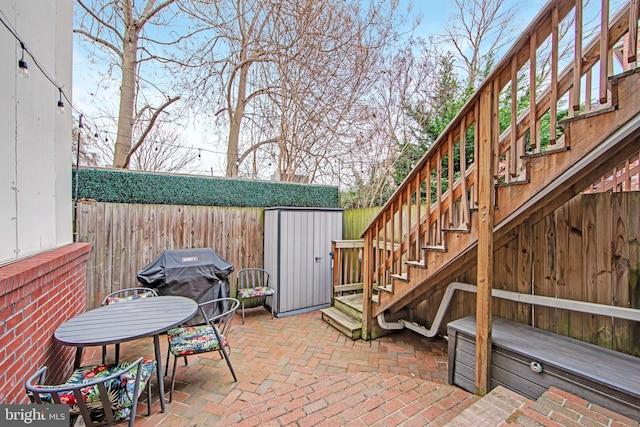 view of patio / terrace featuring stairway, a storage shed, an outdoor structure, and fence