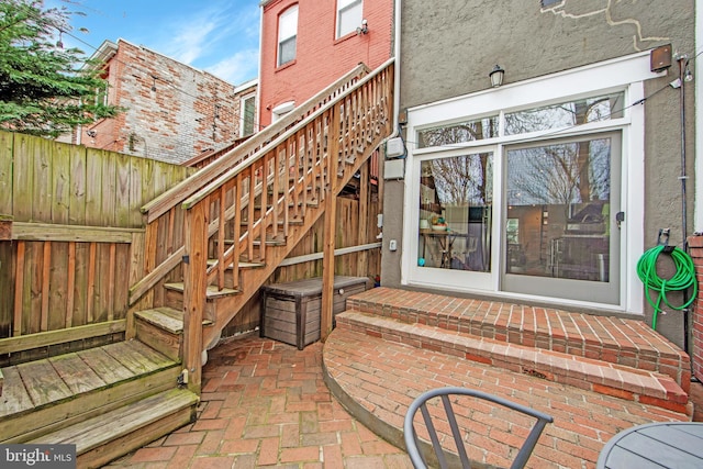 entrance to property with a patio, stucco siding, and fence