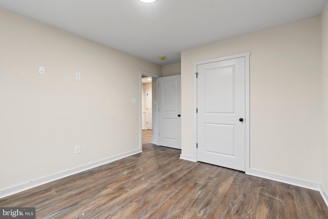 unfurnished bedroom featuring a closet, baseboards, and wood finished floors