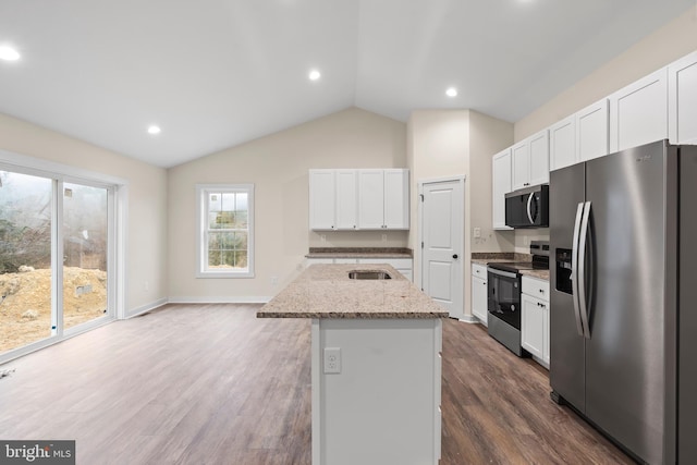 kitchen featuring white cabinets, appliances with stainless steel finishes, a kitchen island with sink, and light stone countertops