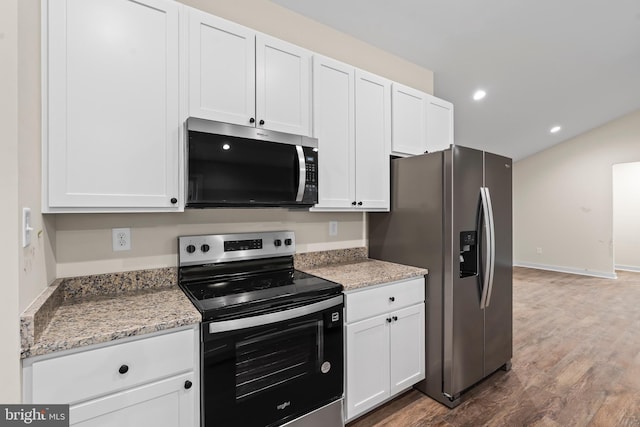 kitchen with stainless steel appliances, light stone counters, wood finished floors, and white cabinetry