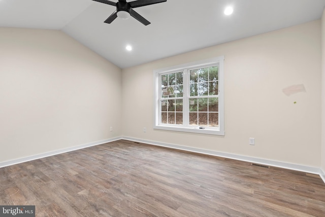 spare room with baseboards, visible vents, vaulted ceiling, and wood finished floors