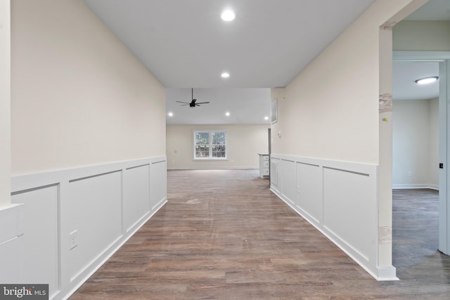 corridor with recessed lighting, wainscoting, a decorative wall, and wood finished floors