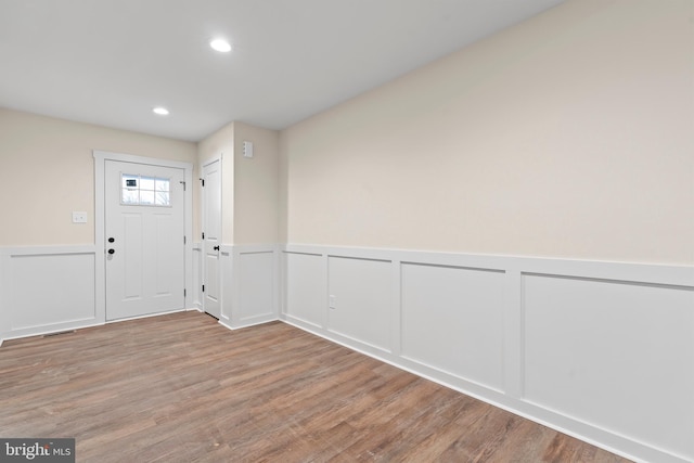 entrance foyer with visible vents, wainscoting, wood finished floors, a decorative wall, and recessed lighting