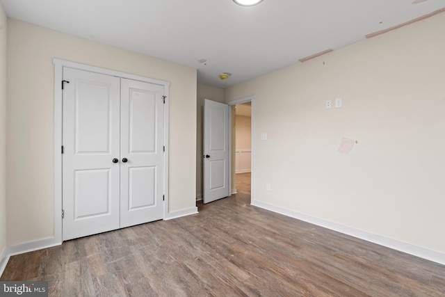 unfurnished bedroom featuring a closet, baseboards, and wood finished floors